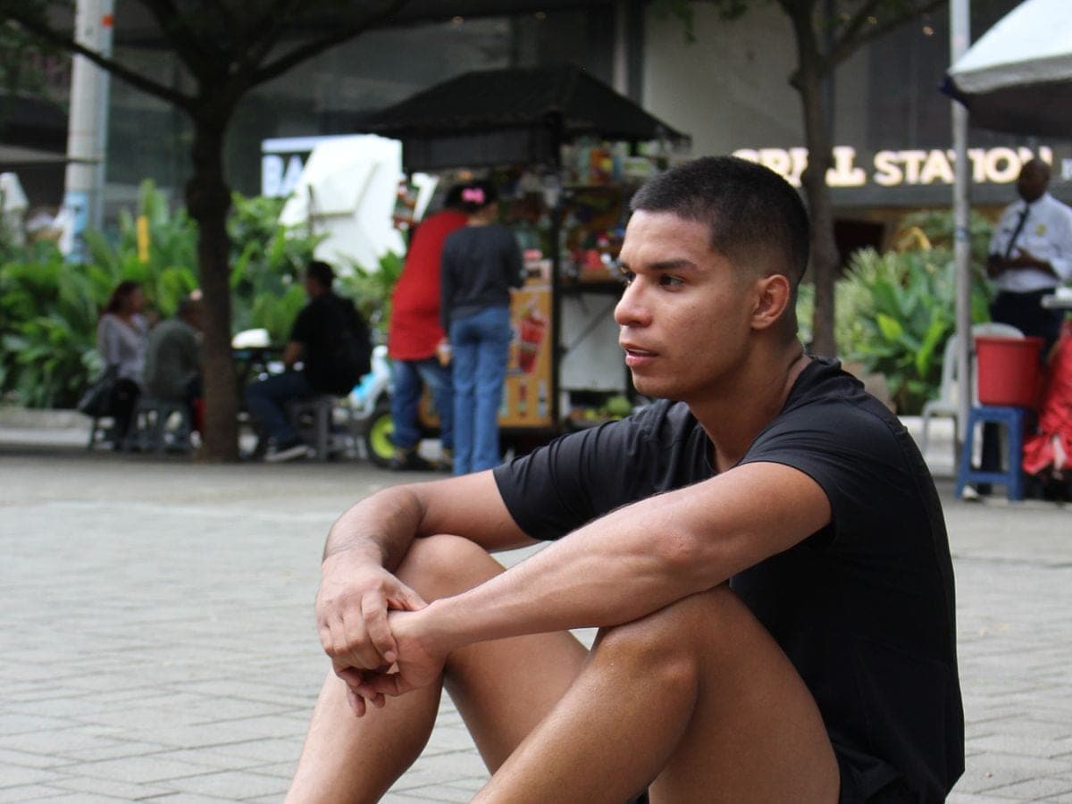 Un atleta descansa sentado en el parque después de entrenar.